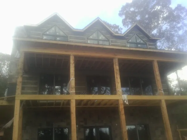 Dormers and porch framing on a large log home under construction — Roof Coating work by our crew in Ava